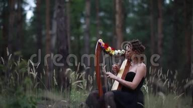 女<strong>竖琴</strong>手坐在森林里弹<strong>竖琴</strong>。 特写镜头。